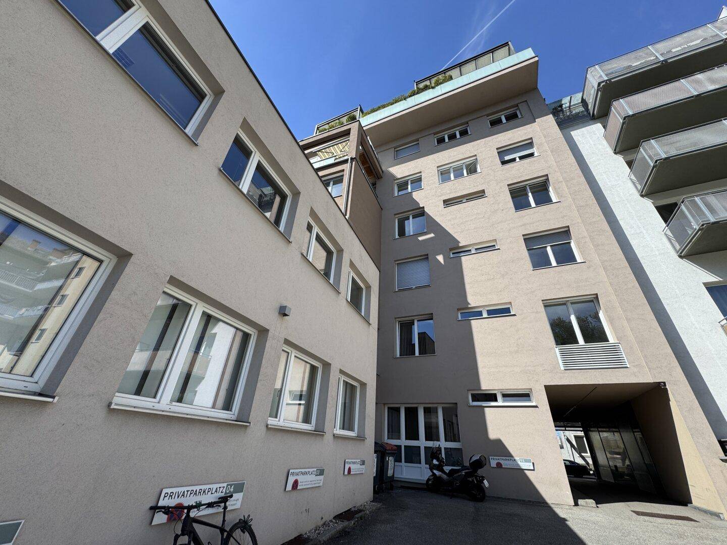 Gebäudekomplex mit moderner Architektur, privatem Parkplatz und Zugang zu den oberen Etagen.