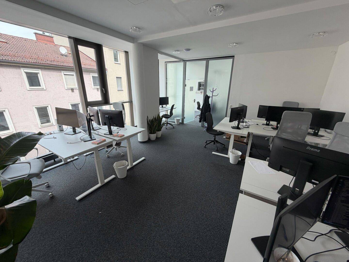 Großes, offenes Büro mit vielen Arbeitsplätzen, großen Fenstern und Blick auf die umliegende Stadt.