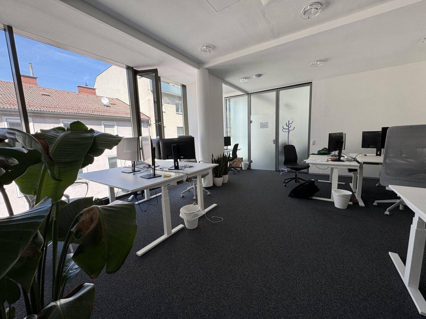 Großes, offenes Büro mit vielen Arbeitsplätzen, großen Fenstern und Blick auf die umliegende Stadt.