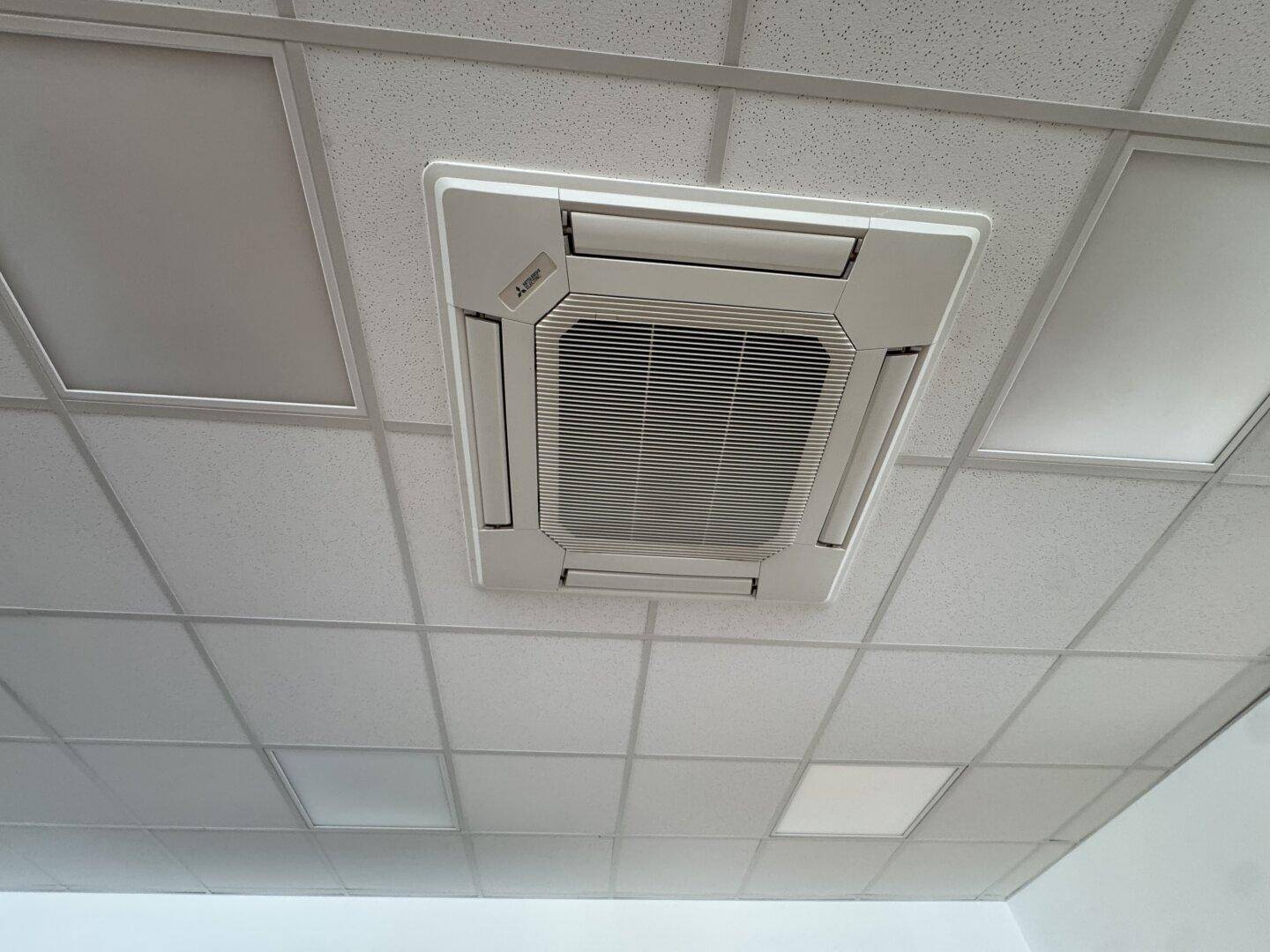 Deckenmontierte Klimaanlage in einem Bürogebäude mit Rasterdecke.
