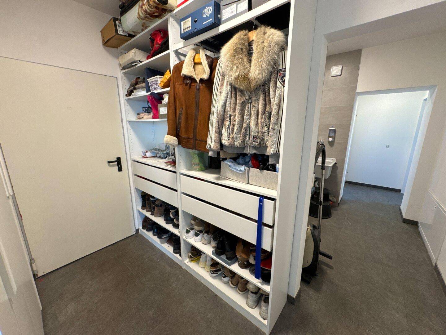 Geräumiger begehbarer Kleiderschrank mit offenen Regalen und viel Stauraum für Kleidung und Schuhe.