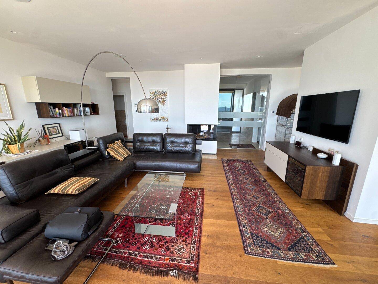 Gemütliches Wohnzimmer mit Ledersofa, Holzboden und einem modernen Kamin, der zum Entspannen einlädt.