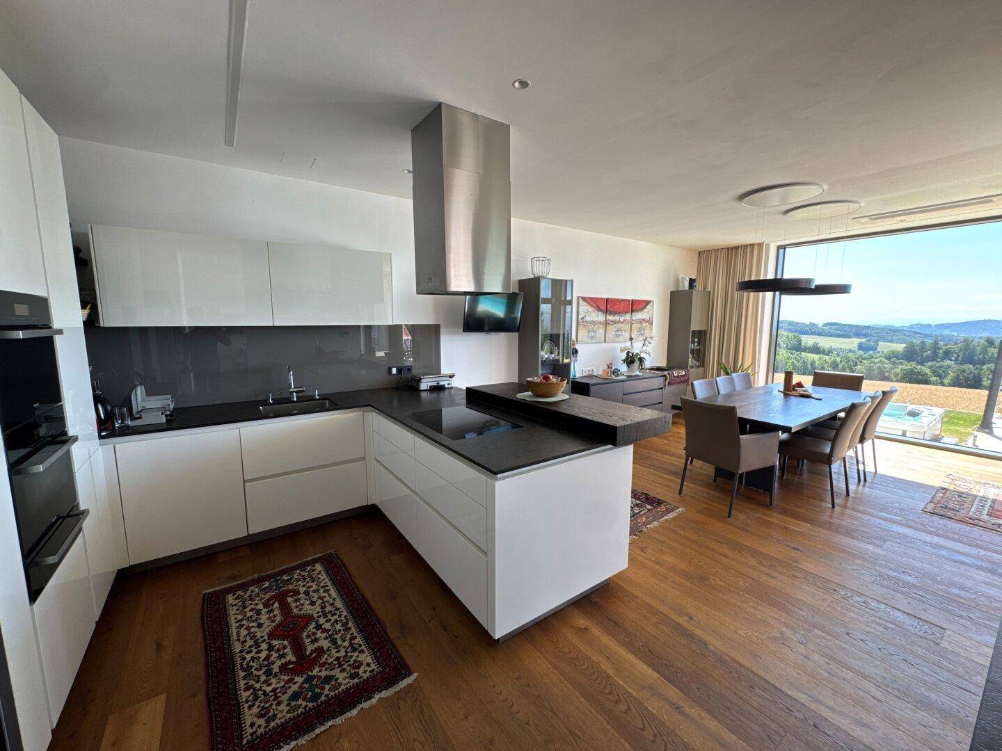 Moderne offene Küche mit Essbereich, Holzboden und raumhohen Fenstern mit weitem Ausblick.
