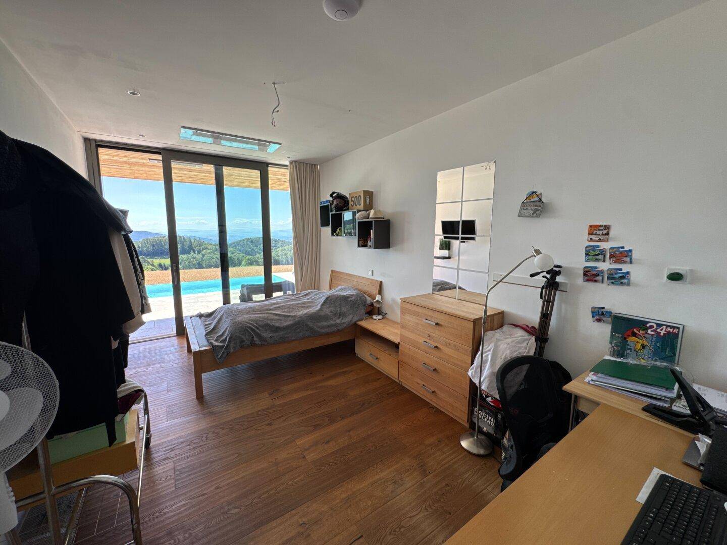 Helles Schlafzimmer mit Holzboden, direktem Zugang zum Poolbereich und Panoramablick.
