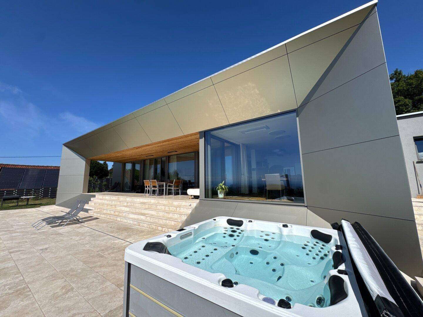 Moderner Whirlpool auf der großzügigen Terrasse einer Villa mit beeindruckender Architektur und Weitblick.