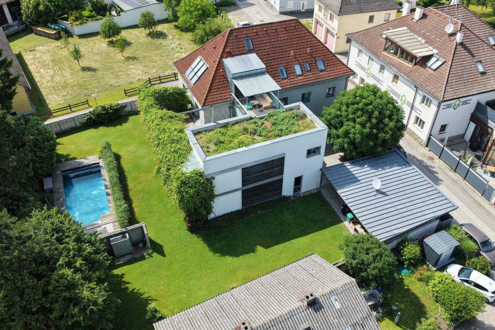 Weitläufige Luftaufnahme des Hauses mit Garten, Poolbereich und umliegender Bebauung.
