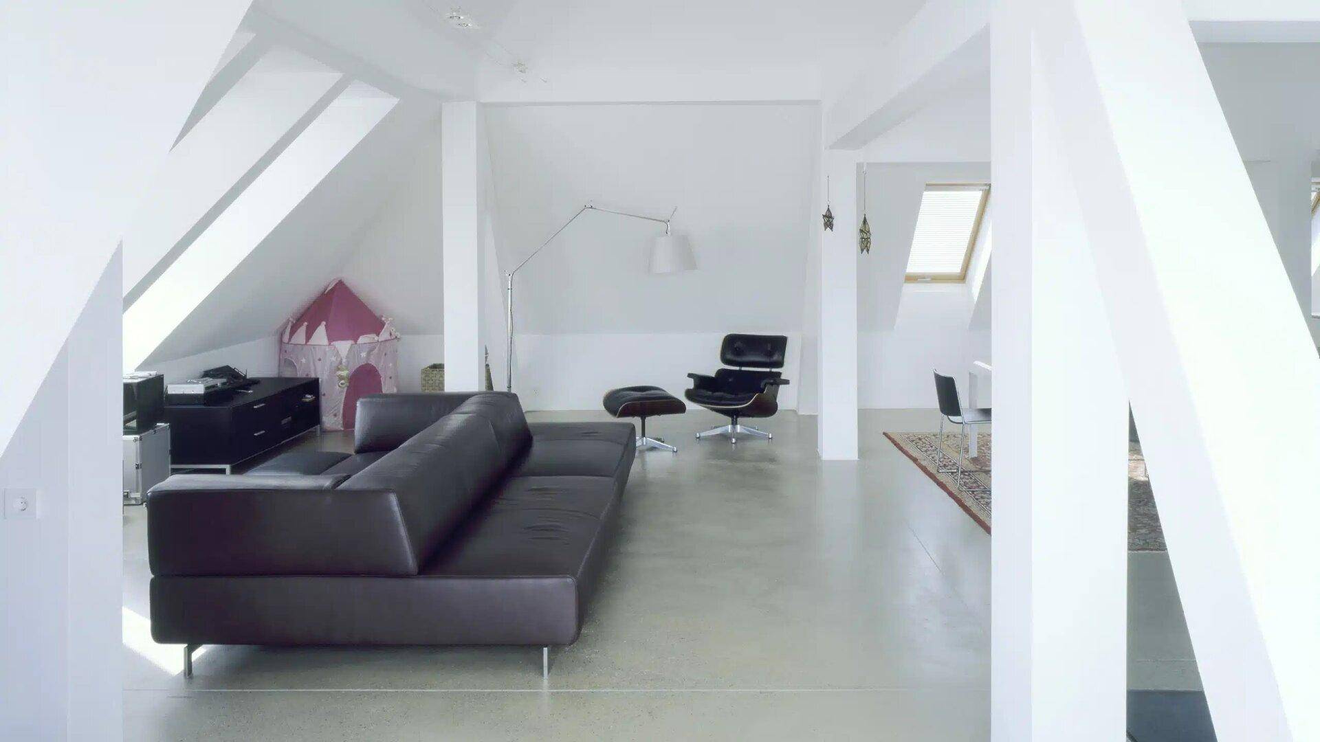 Geräumiges Wohnzimmer im Dachgeschoss mit schrägen Wänden und minimalistischer Einrichtung.