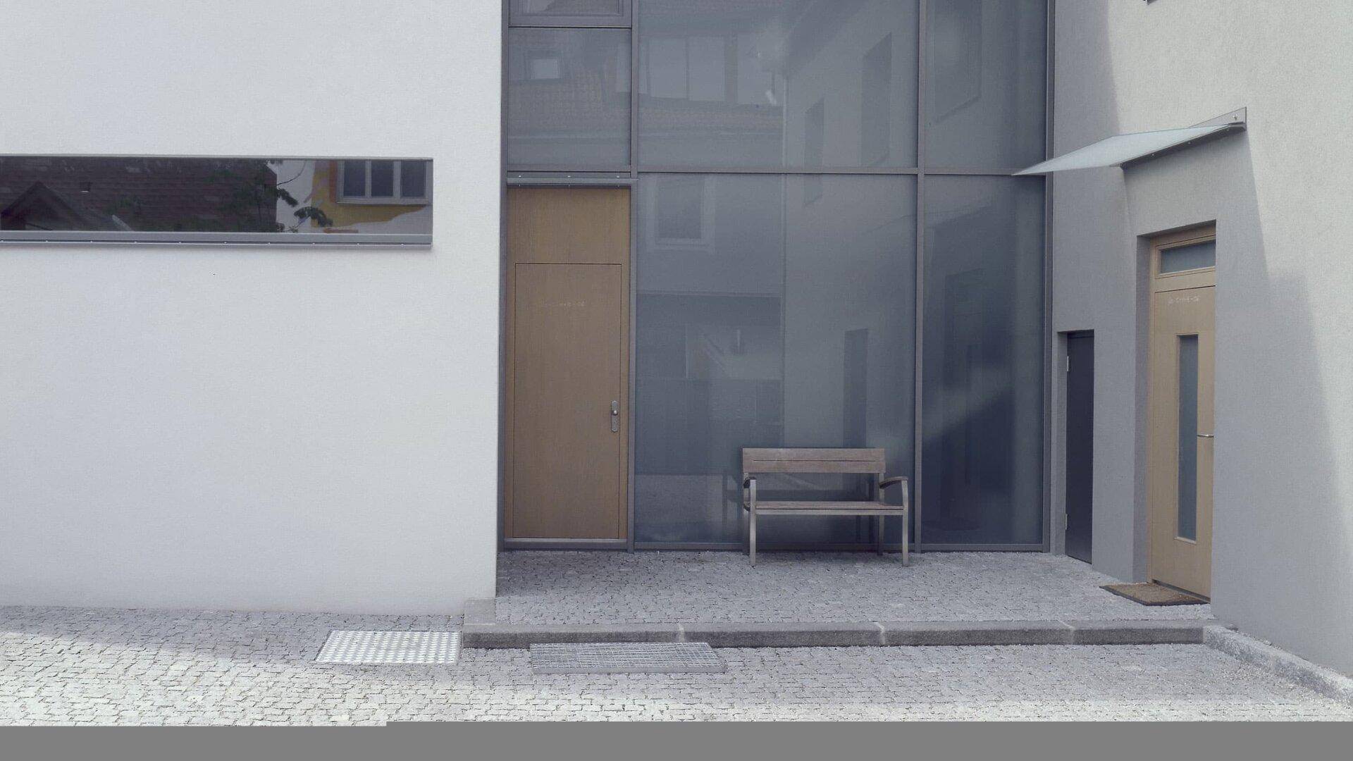 Moderner Eingangsbereich mit großer Glasfront und Holztür.