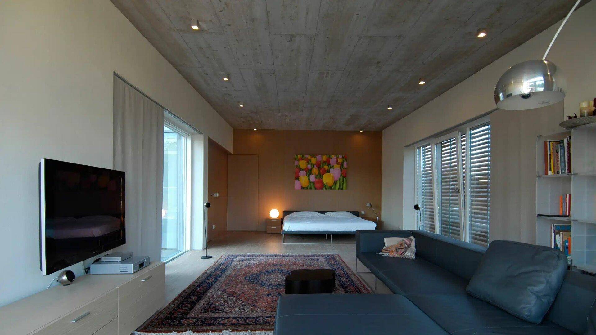 Schlafzimmer mit integriertem Wohnbereich, großem Bett und Kunstwerk an der Wand.