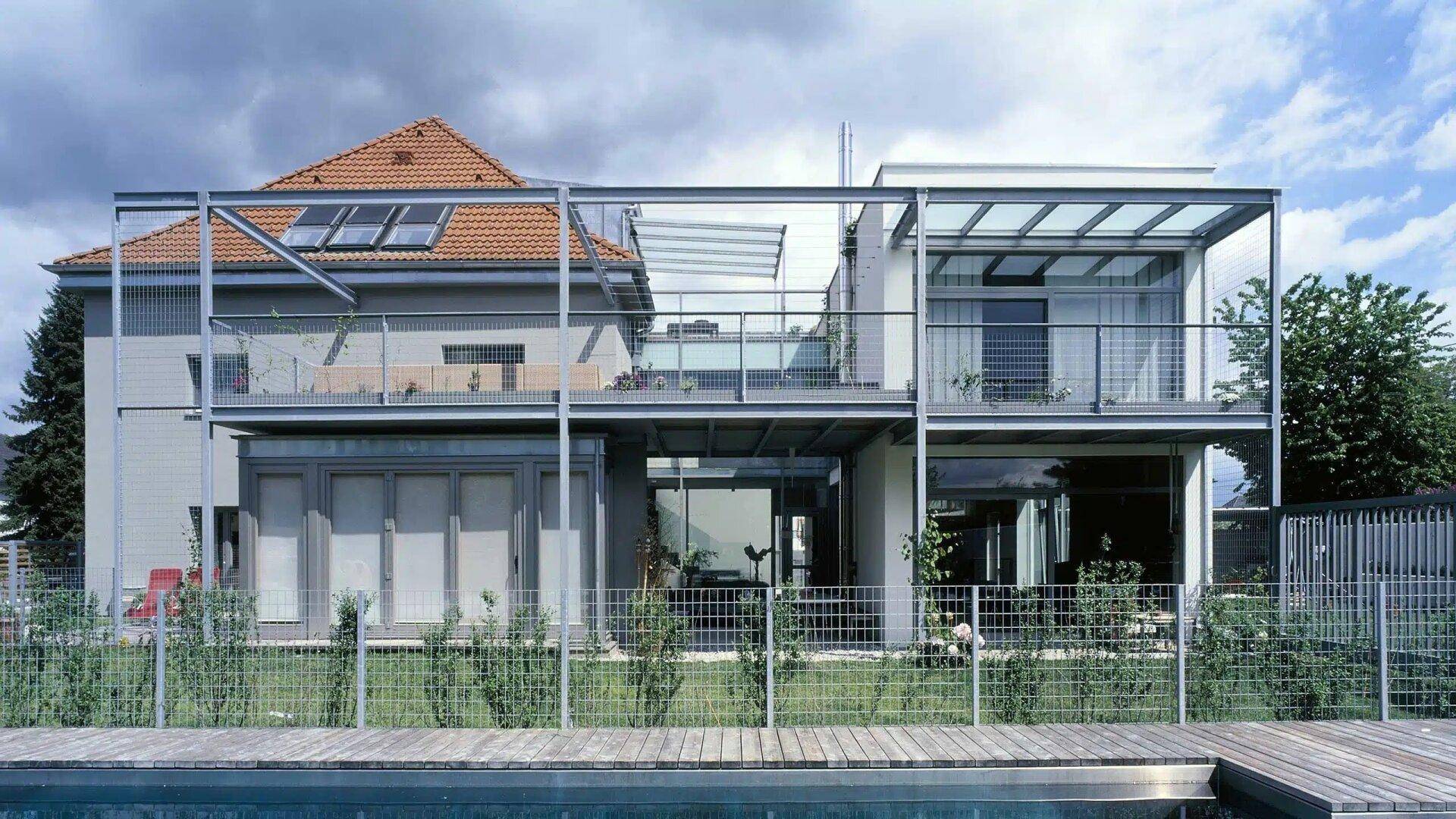 Rückansicht des Hauses mit großzügigen Balkonen, Glasfronten und Poolbereich.
