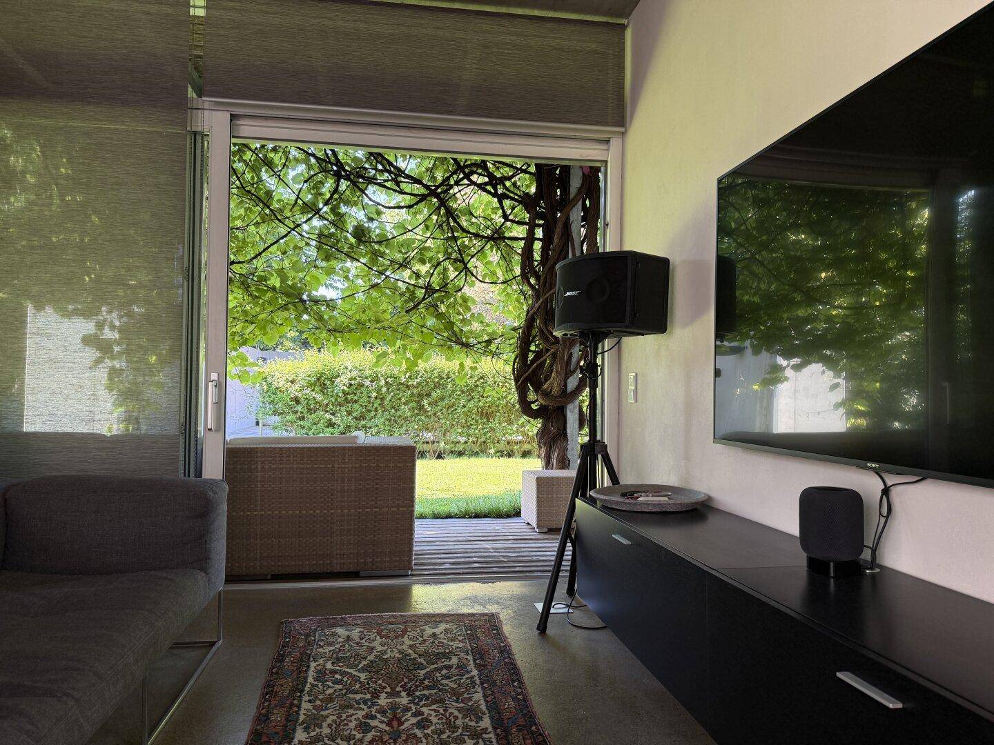 Wohnzimmer mit Blick in den Garten, großem Fernseher und gemütlicher Einrichtung.