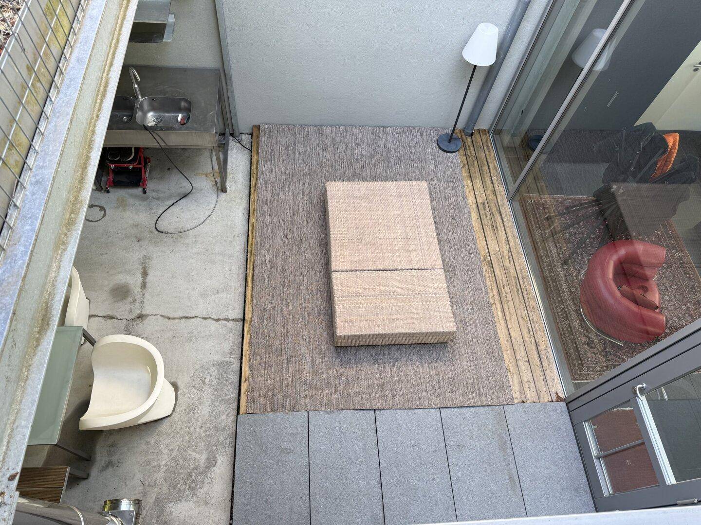Draufsicht auf den Terrassenbereich mit Rattanliege und angrenzender Außenküche.