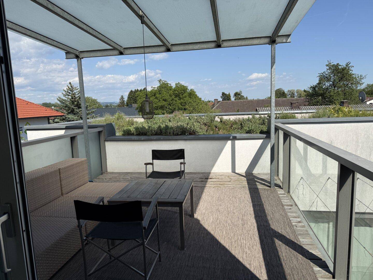 Sonnige Dachterrasse mit bequemen Gartenmöbeln und weitem Blick über die Umgebung.