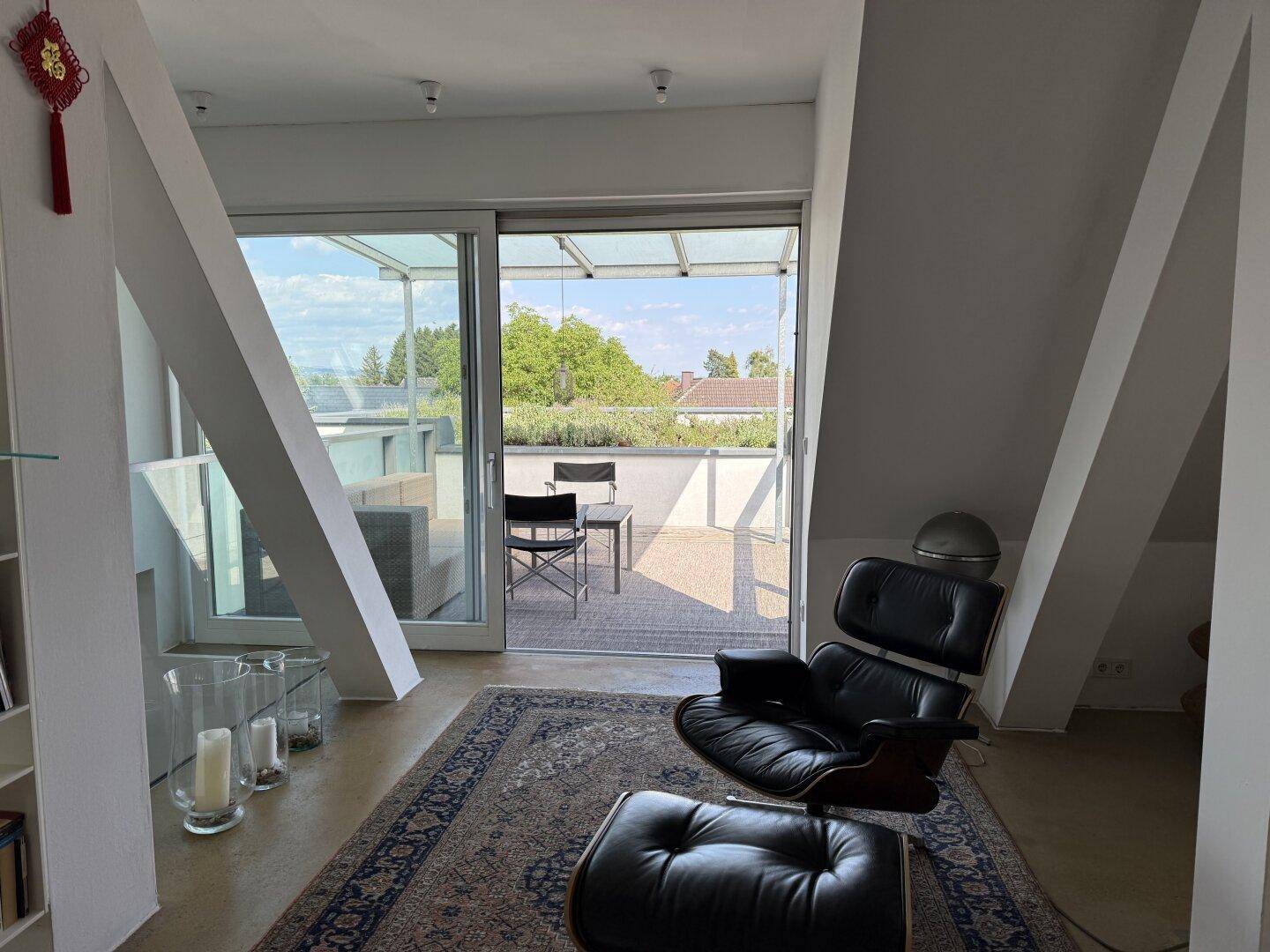 Heller Wohnbereich mit schrägen Decken und direktem Zugang zur sonnigen Dachterrasse.
