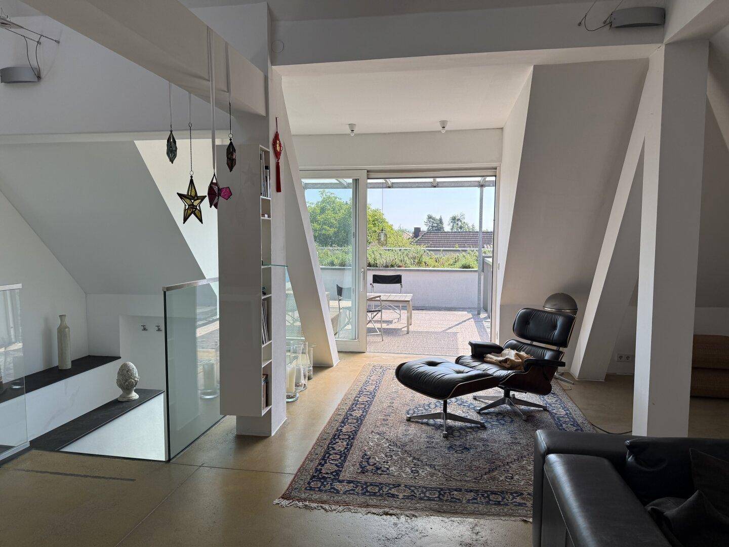 Heller Wohnbereich mit elegantem Sessel und direktem Zugang zur großzügigen Dachterrasse.