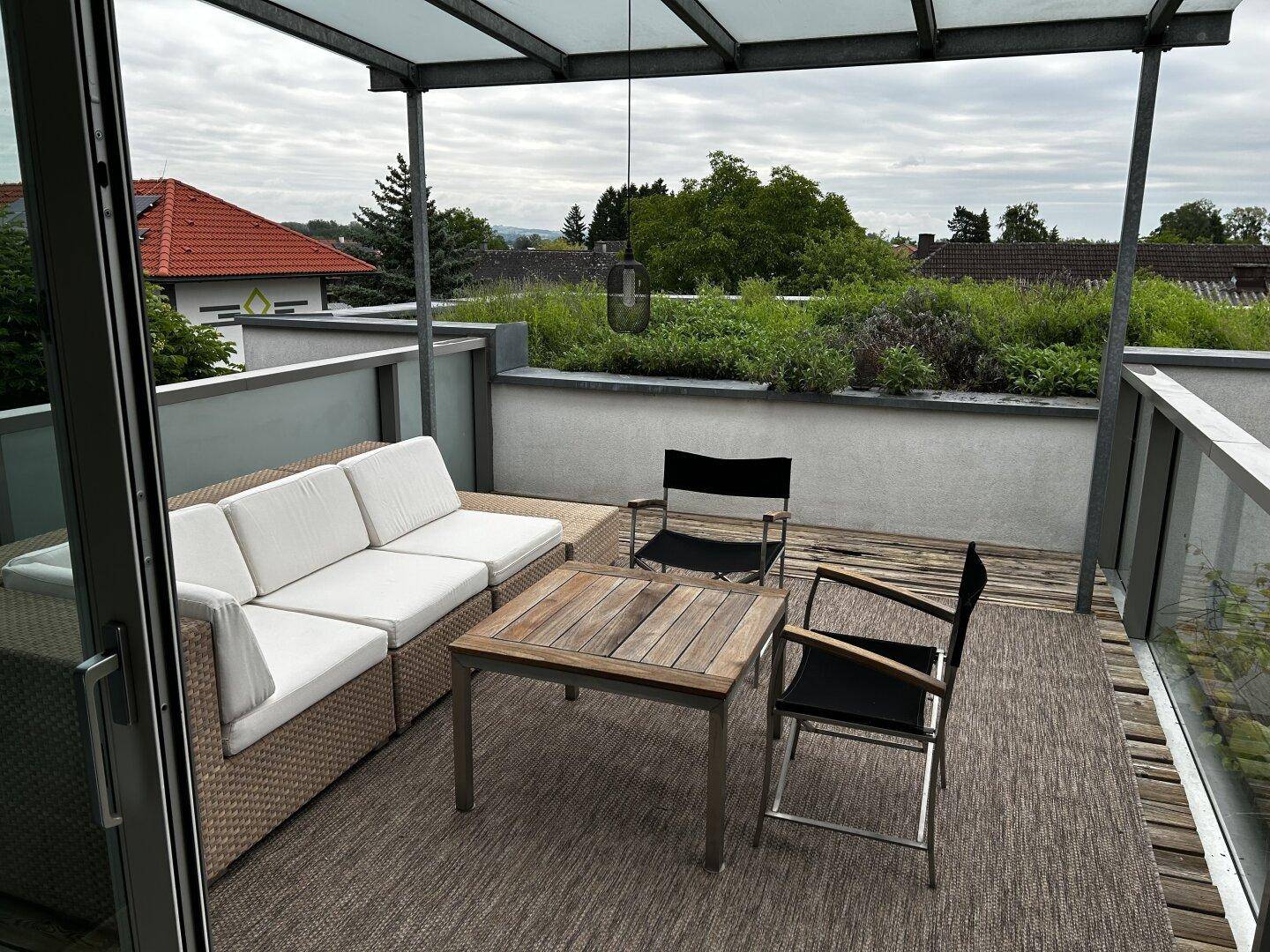 Geräumige Dachterrasse mit bequemen Lounge-Möbeln und Blick auf die bewölkte Landschaft.