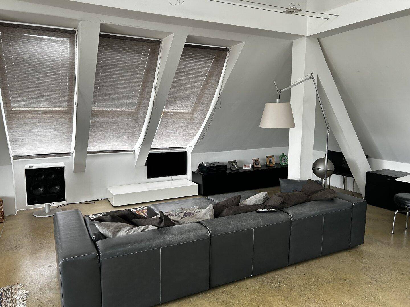 Modernes Wohnzimmer mit schrägen Decken, Dachfenstern und großem Sofa für entspannte Stunden.