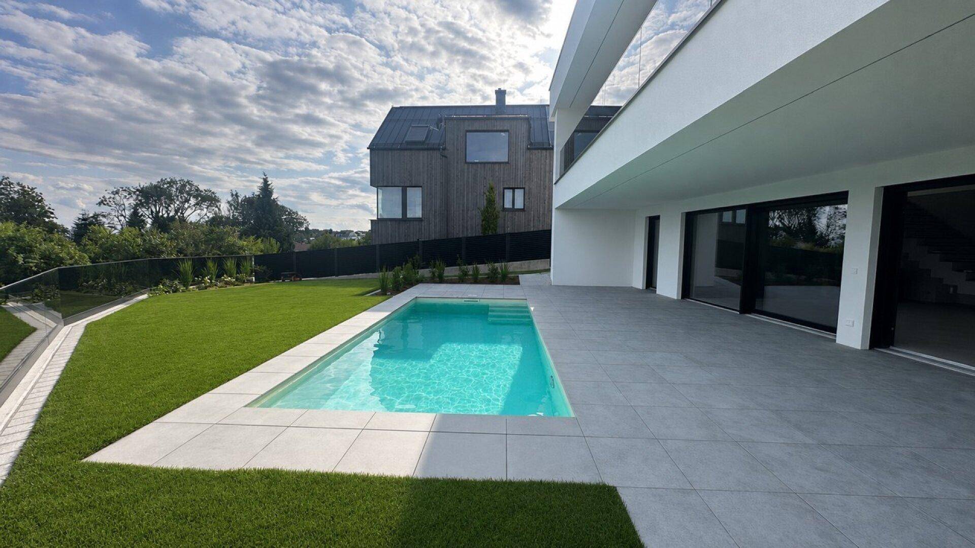 Außenbereich mit rechteckigem Pool, großzügiger Terrasse und Blick auf die umliegende Natur.