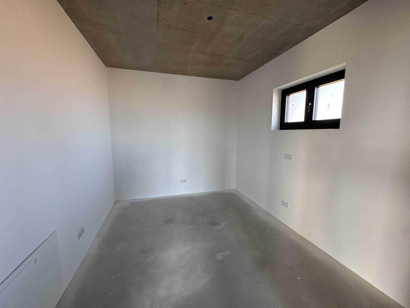 Kleiner Raum im Rohbau mit einem Fenster, ideal als Schlafzimmer oder Arbeitszimmer.