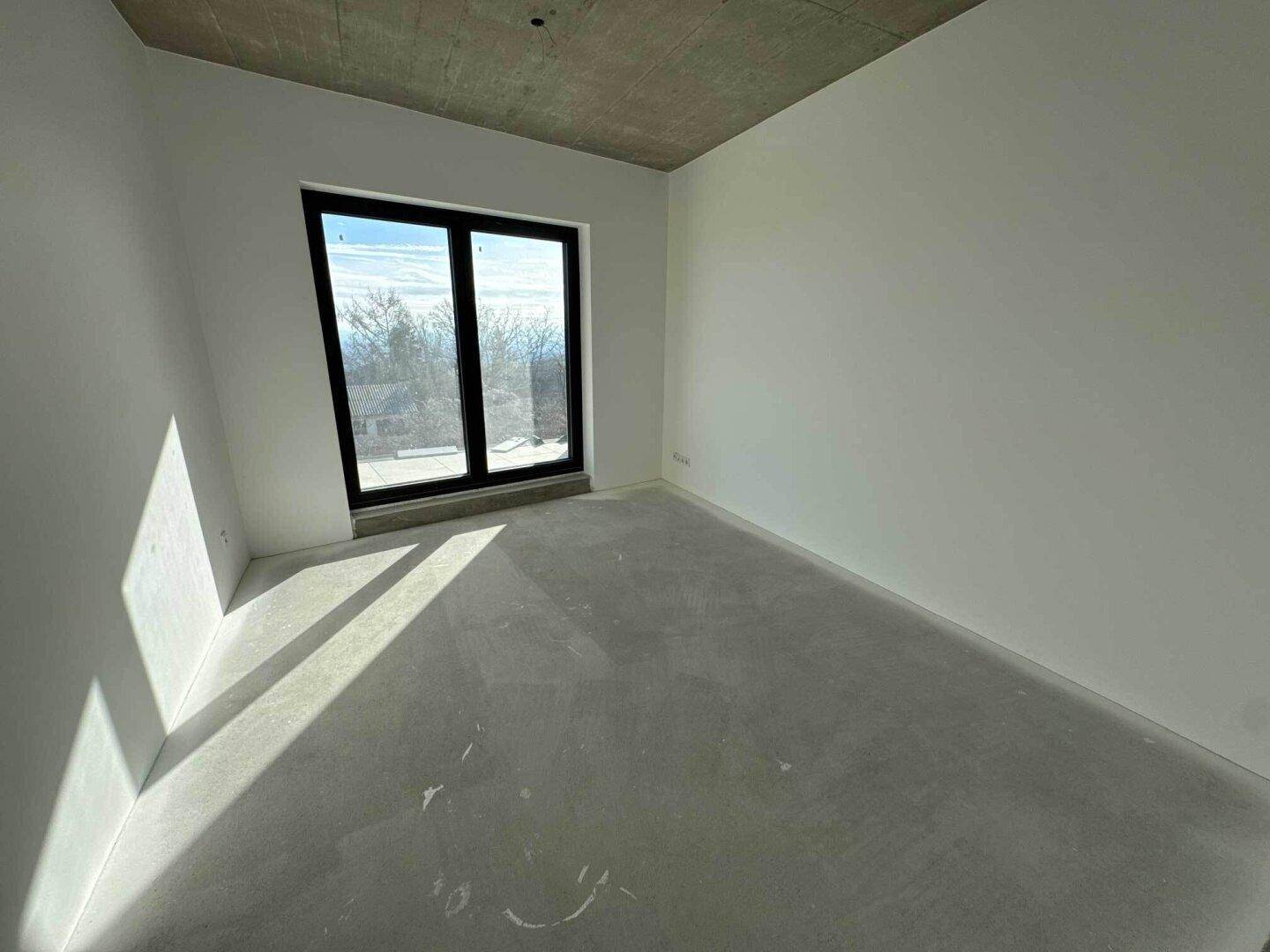 Lichtdurchflutetes Zimmer im Rohbau mit weitem Ausblick, ideal für individuelle Gestaltung.