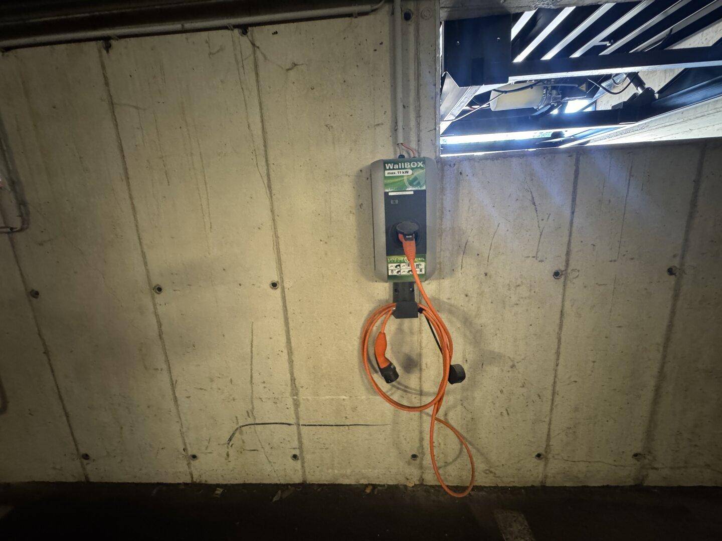 Ladestation für Elektrofahrzeuge an einer Betonwand in einer Tiefgarage.