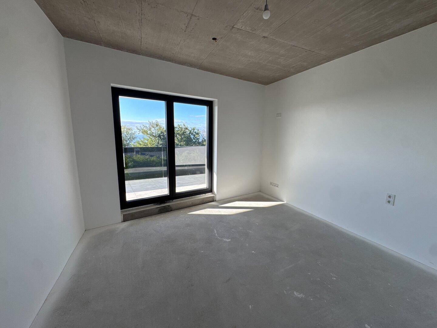 Helles Schlafzimmer im Rohbau mit weißen Wänden und großer Schiebetür zum Außenbereich.