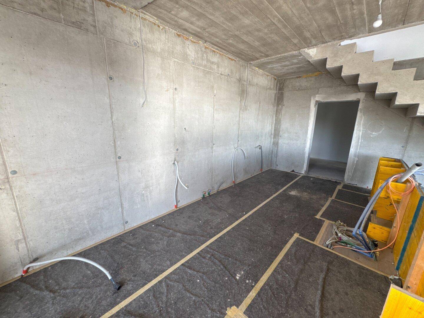 Rohbau-Flur mit Sichtbetonwänden und -decke, vorbereitet für den weiteren Ausbau.