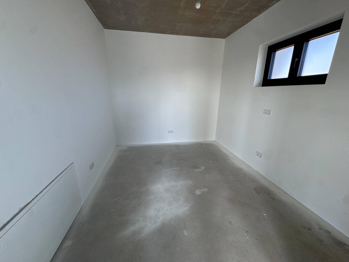 Kleiner Raum im Rohbau mit weißen Wänden und einem Fenster, ideal als Büro oder Abstellraum.