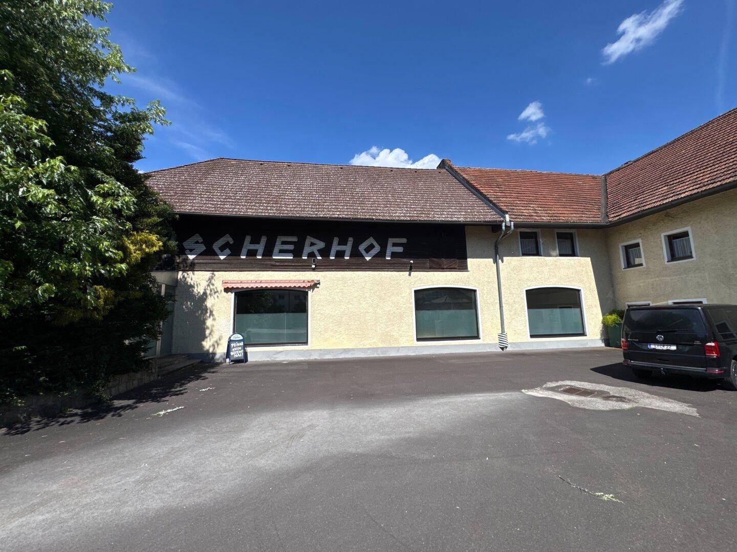 Seitenansicht eines traditionellen Gebäudes mit großem Parkplatz unter blauem Himmel.