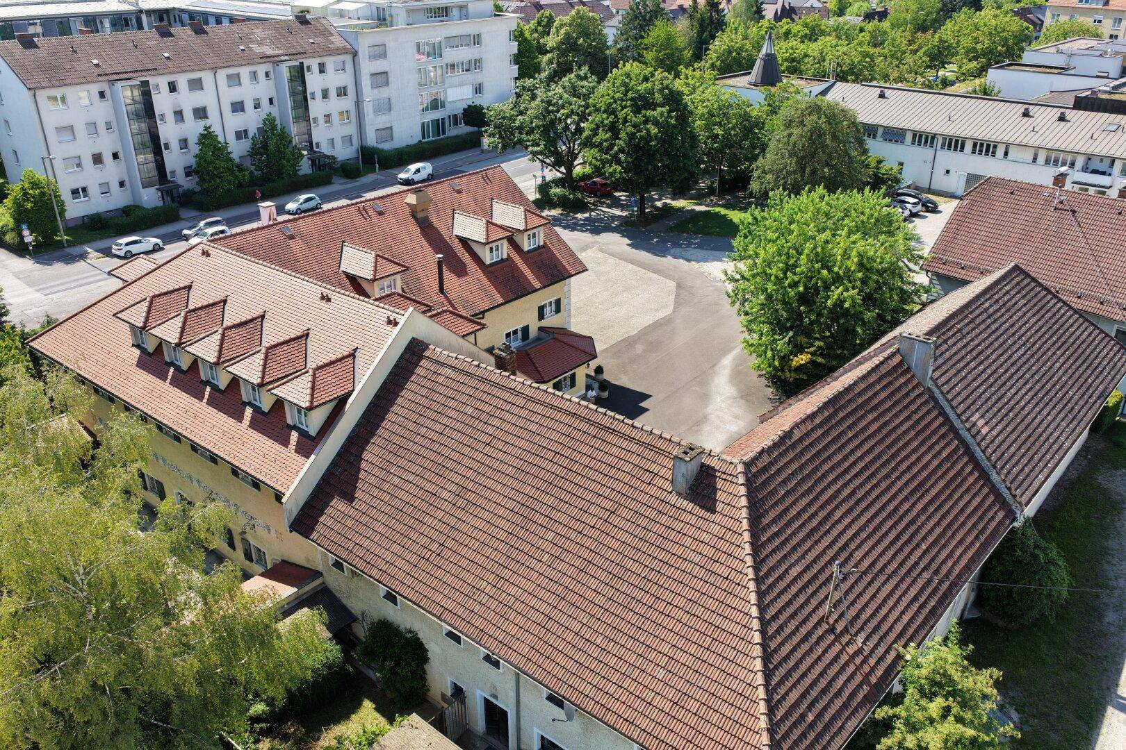 Luftaufnahme des Anwesens mit umliegenden Gebäuden und viel Grün in städtischer Umgebung.