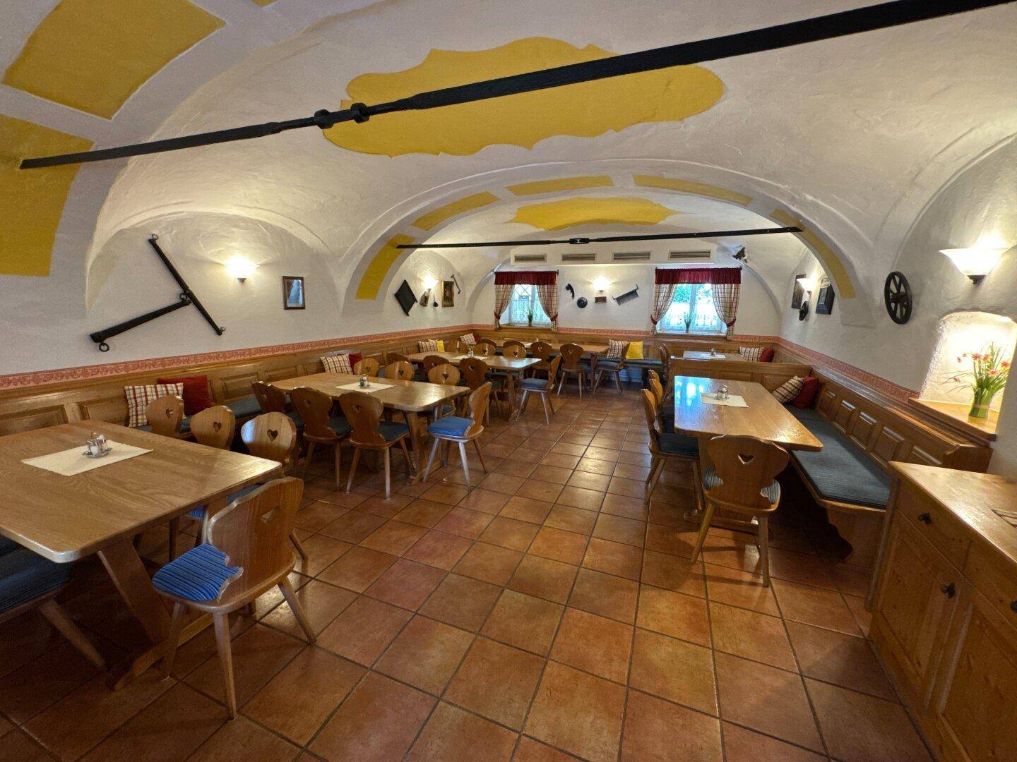 Rustikaler Speisesaal mit Gewölbedecke, Holztischen und Bänken, traditionell eingerichtet.