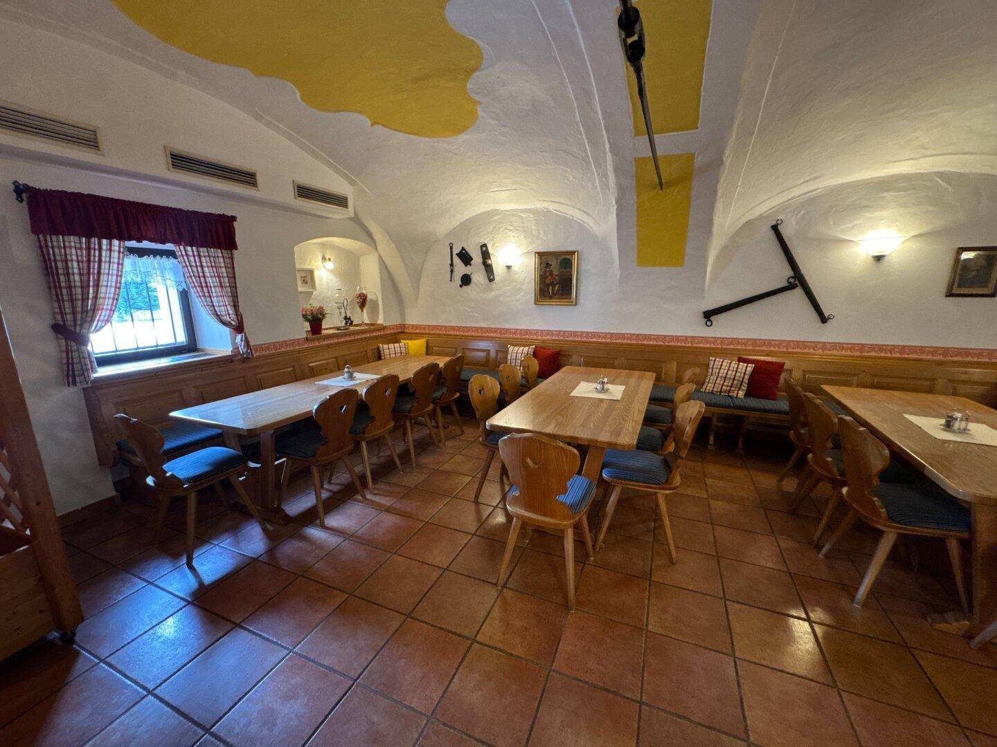 Rustikaler Speisesaal mit Gewölbedecke, Holztischen und Bänken, traditionell eingerichtet.