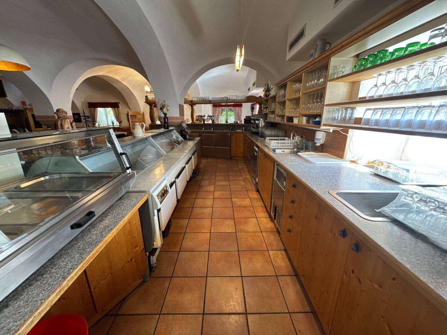 Gewerbliche Küche mit Theke, Kühlvitrinen und Fliesenboden, für Gastronomie geeignet.