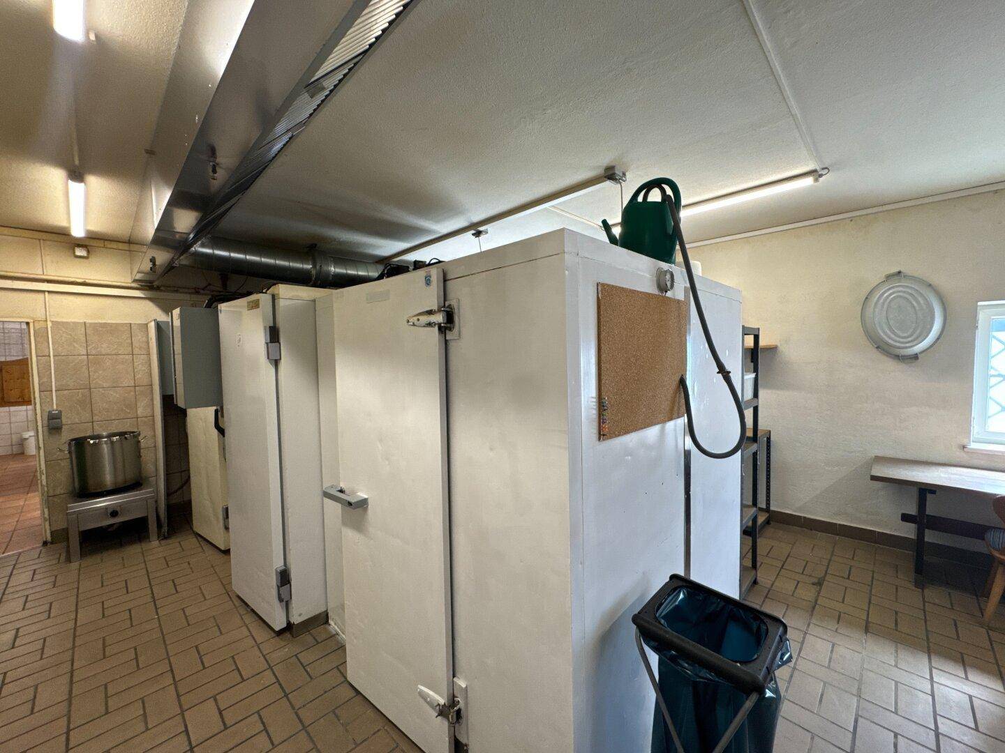 Großer Lagerraum mit mehreren Kühl- und Gefrierschränken sowie einem gefliesten Boden.