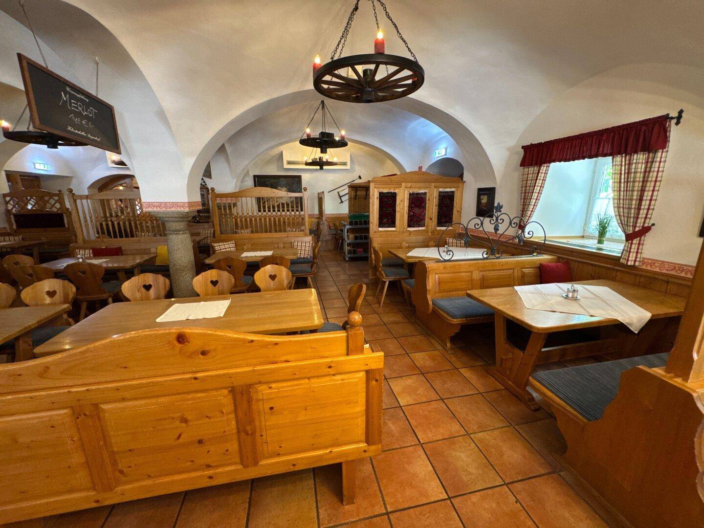 Geräumiger Speisesaal im traditionellen Stil mit Holzbänken, Tischen und gewölbter Decke.