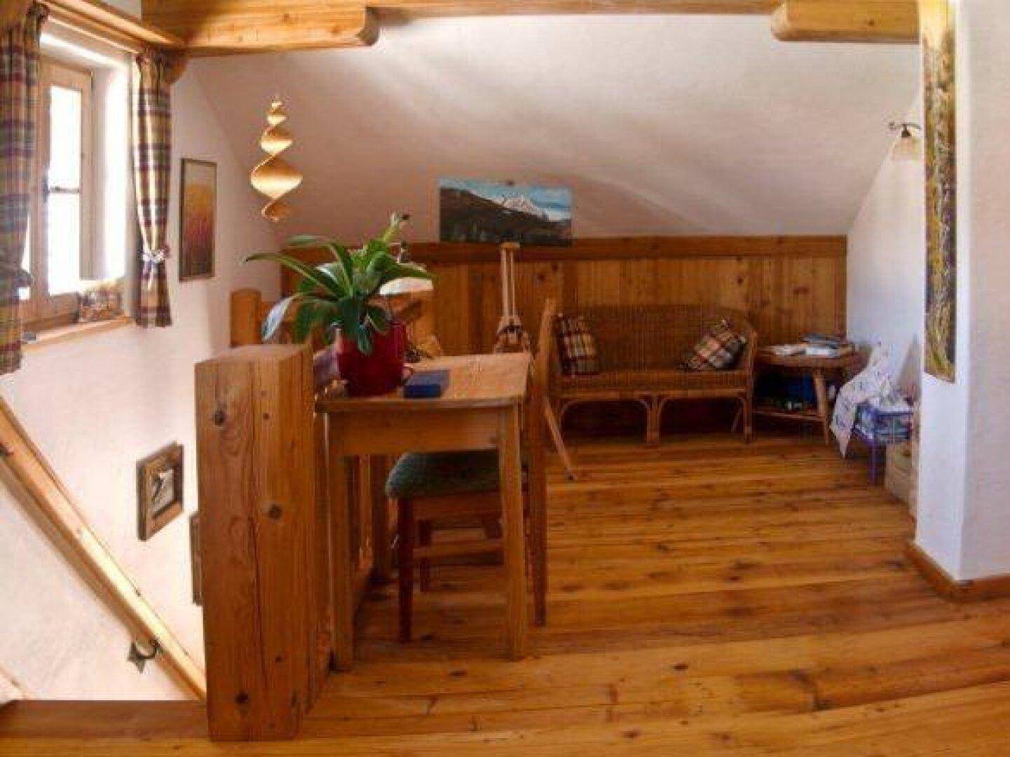 Heller Dachboden-Wohnbereich mit schrägen Decken, Holzboden und rustikalen Möbeln.