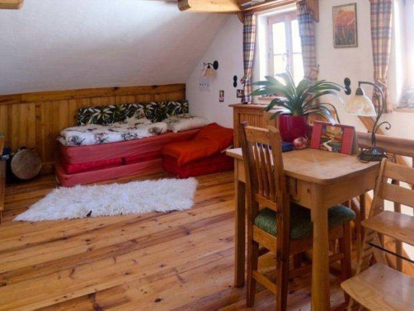 Heller Dachboden-Wohnbereich mit schrägen Decken, Holzboden und gemütlichem Tagesbett.