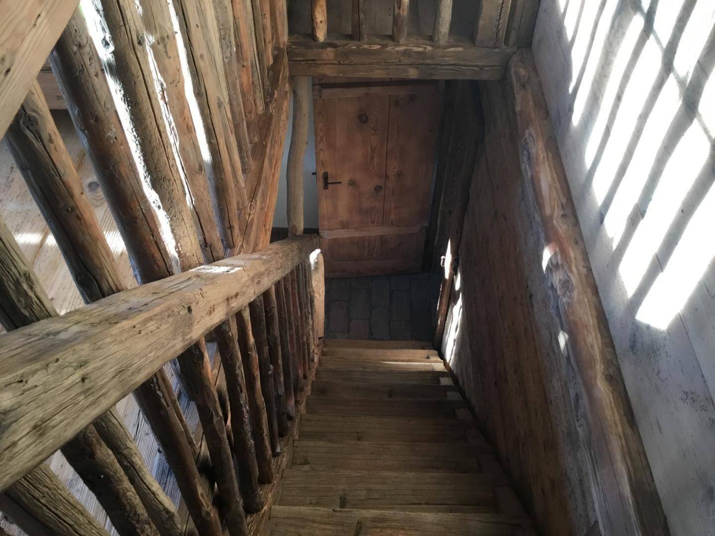 Rustikale Holztreppe mit starkem Lichteinfall, der interessante Schattenmuster erzeugt.