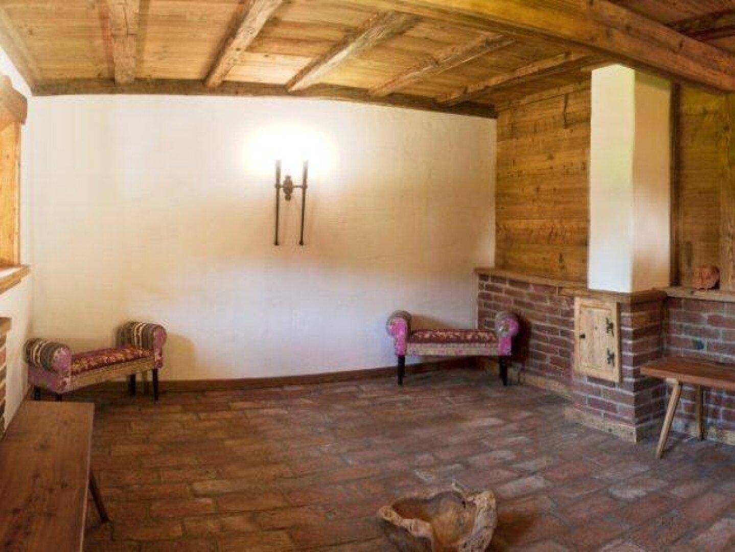 Geräumiger Raum mit Ziegel- und Holzelementen, sichtbaren Balken und Terrakotta-Boden.