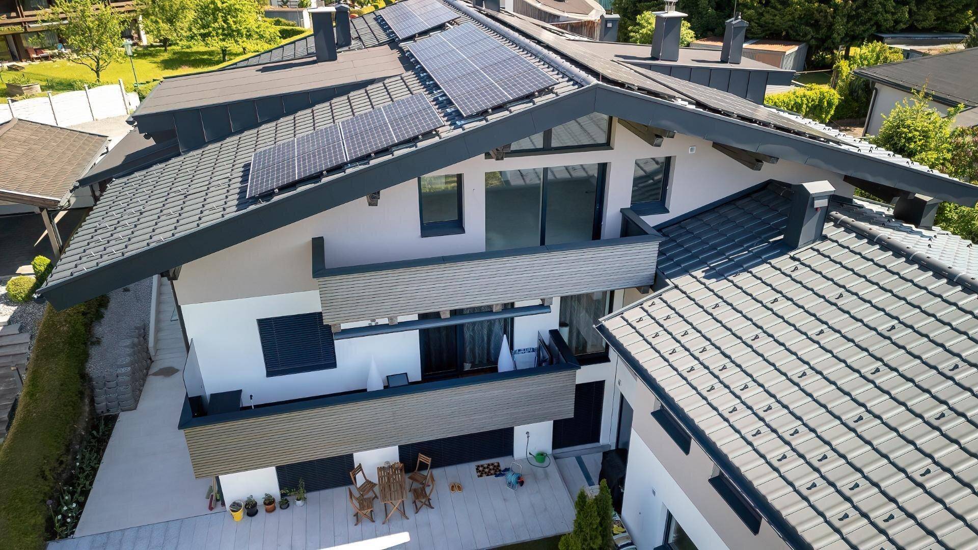 Luftaufnahme eines modernen Wohnhauses mit Solaranlage auf dem Dach und mehreren Balkonen.