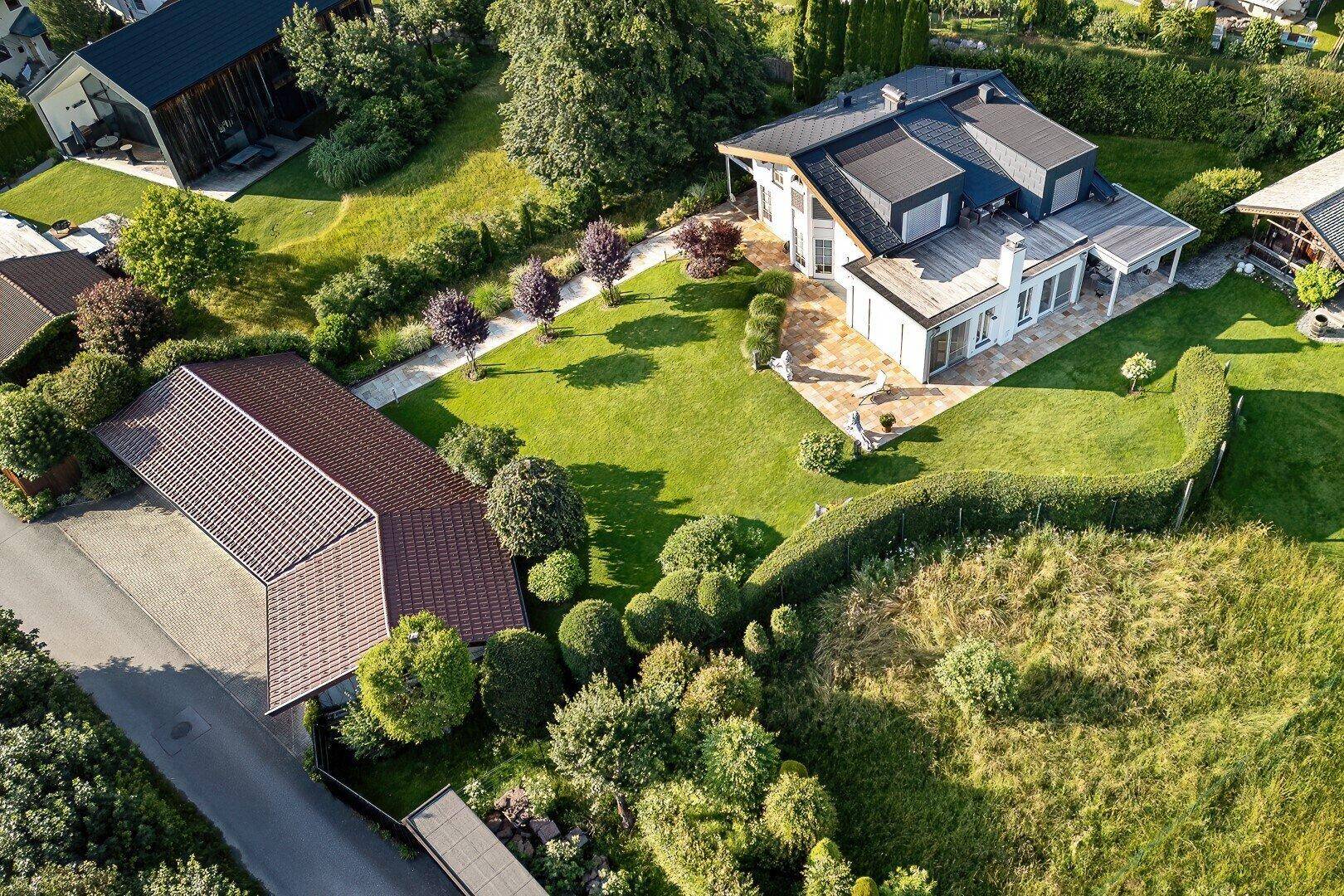 Luftaufnahme des modernen Hauses mit großem Garten, Terrasse und angrenzendem Carport in ländlicher Umgebung.