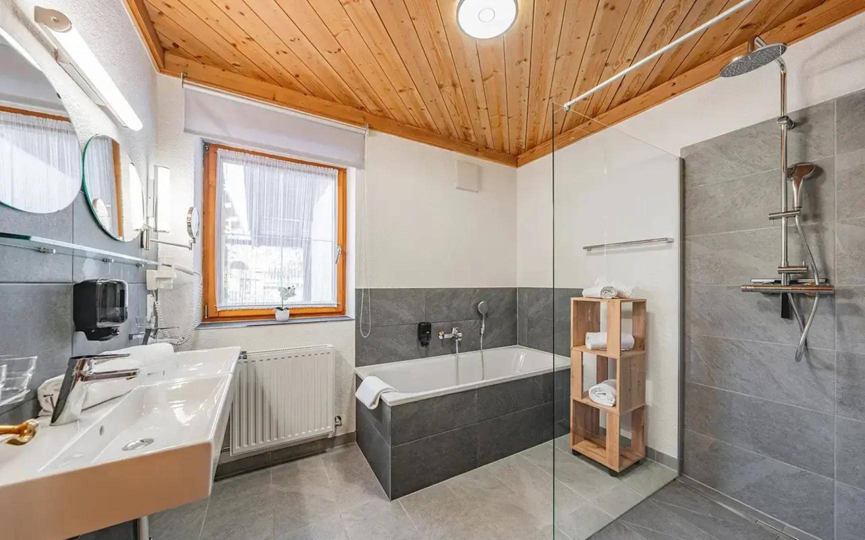 Geräumiges Badezimmer mit begehbarer Dusche, Badewanne, Doppelwaschbecken und einem Fenster.