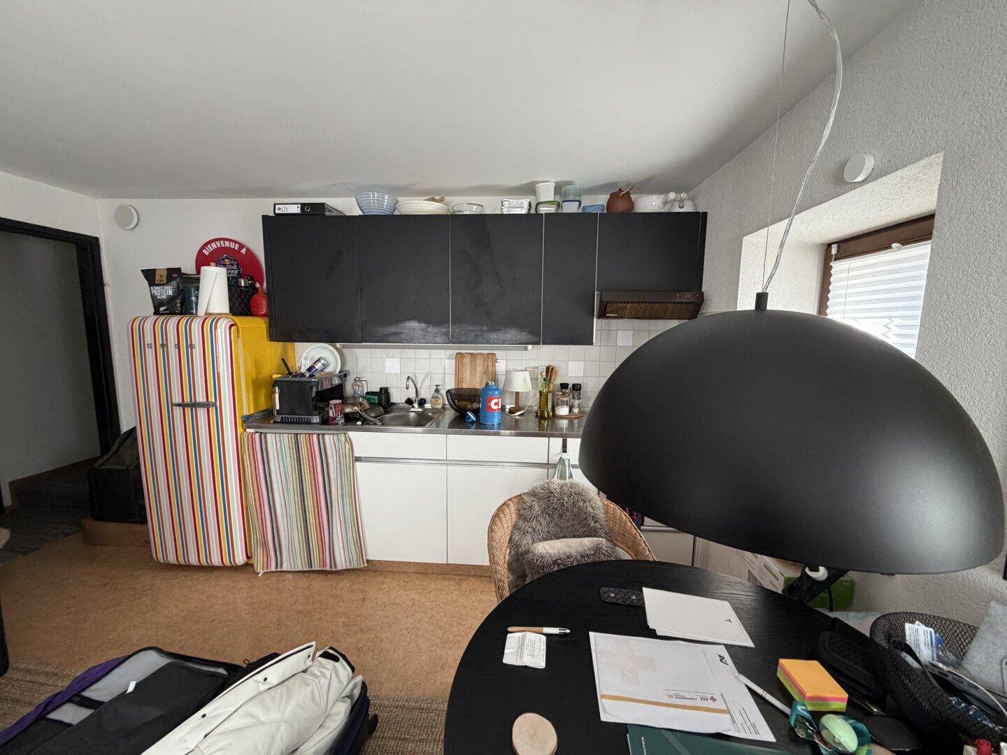 Funktionale Küche mit schwarzen Oberschränken, Retro-Kühlschrank und Korkboden.