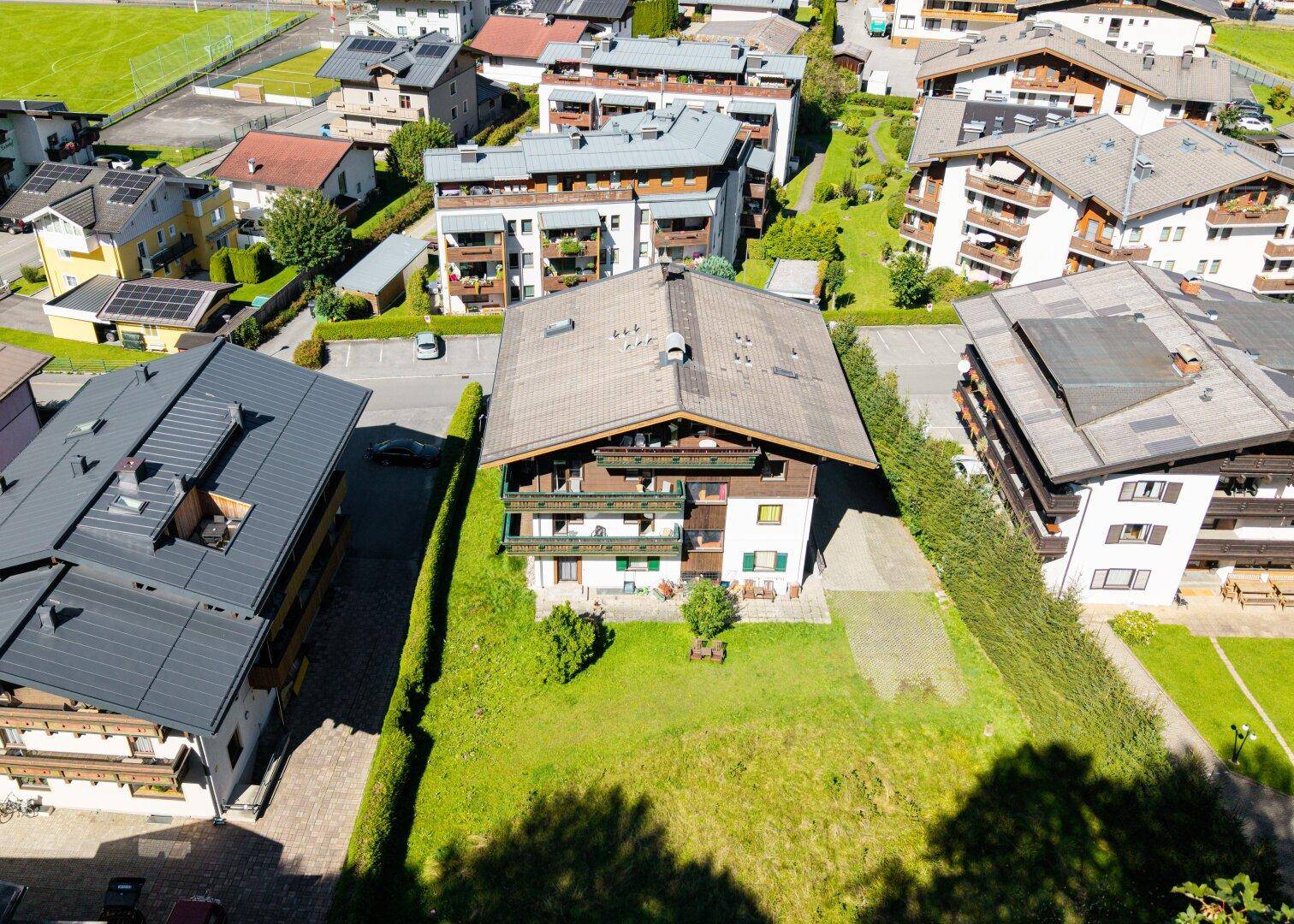 Rückansicht eines Wohnhauses mit großem Gartenbereich und traditionellen Holzbalkonen in sonniger Lage.