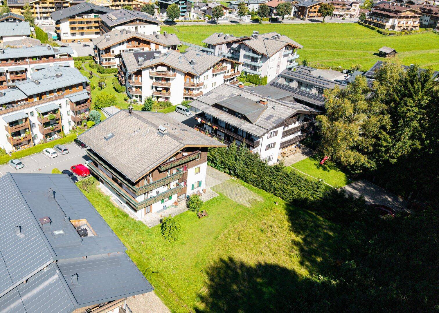 Luftaufnahme eines Gebäudes mit traditioneller Architektur, umgeben von einer weitläufigen Grünfläche und Bäumen.