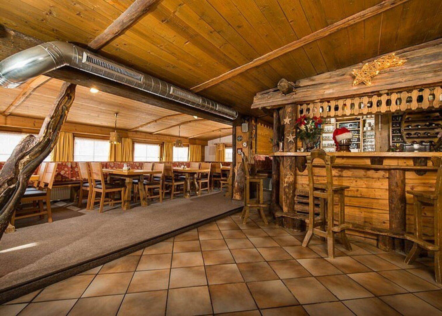 Rustikales Restaurant mit Holztischen, Bänken und einer traditionellen Holzbar, ideal für gesellige Runden.
