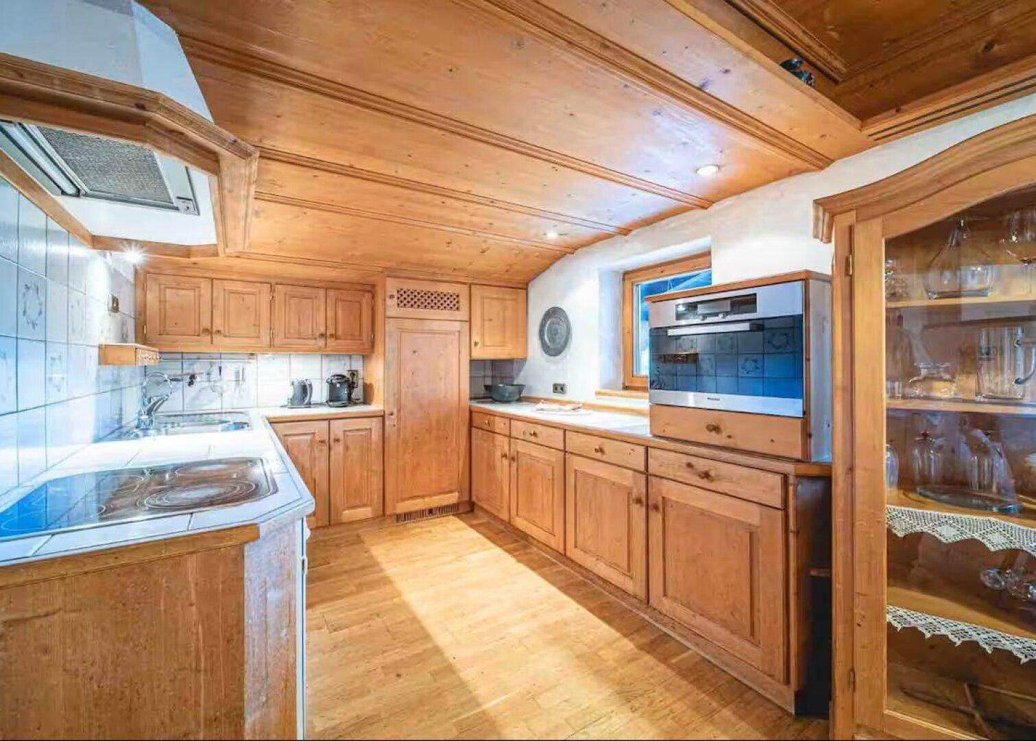Traditionelle Holzküche mit Einbauschränken, Fliesenboden und Holzdecke.