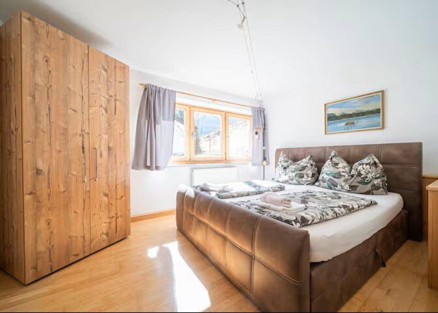Komfortables Schlafzimmer mit Doppelbett, Holzboden und großem Kleiderschrank.