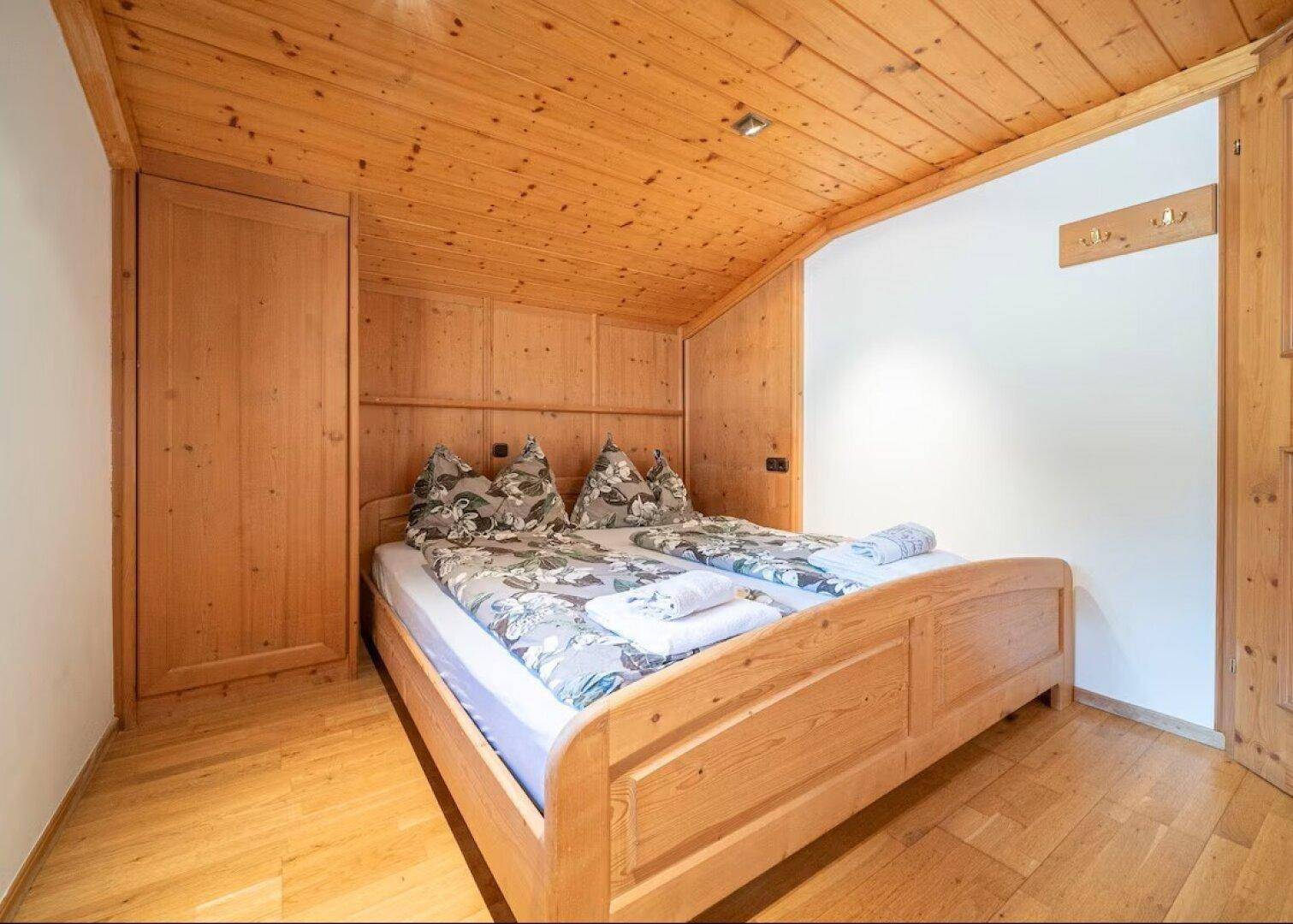 Gemütliches Schlafzimmer mit Holzvertäfelung, Holzboden und Dachschräge.