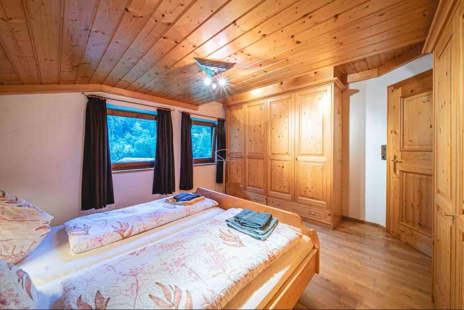 Geräumiges Schlafzimmer mit Holzdecken, Einbauschränken und Holzboden.
